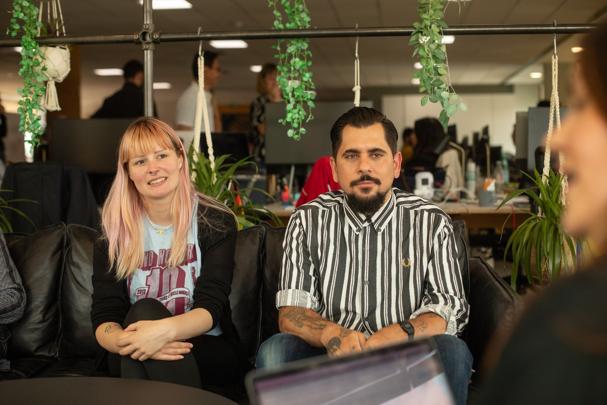 Two INSHUR employees sitting on a black sofa in our vibrant offices