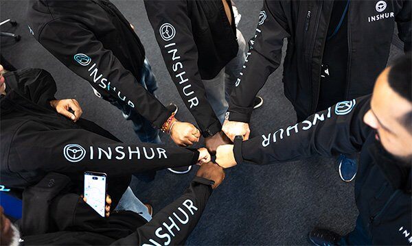 A group of INSHUR employees standing in a circle with their arms extended for a team fistbump